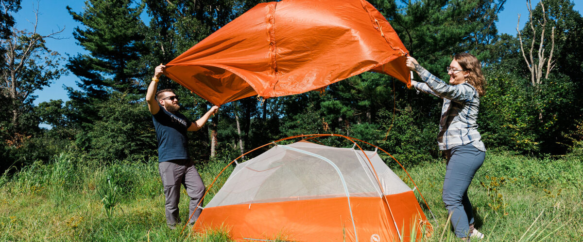 Two people outdoors pitching a tent