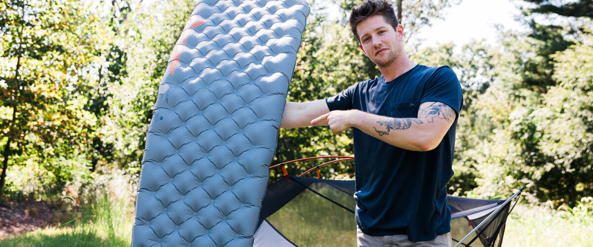 Man outdoors holding a sleeping pad