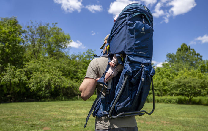 man carrying child outdoors in child carrier