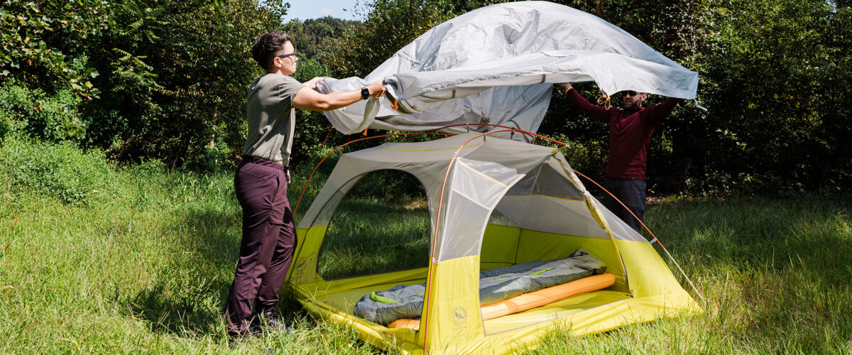 Person setting up tent at campsite