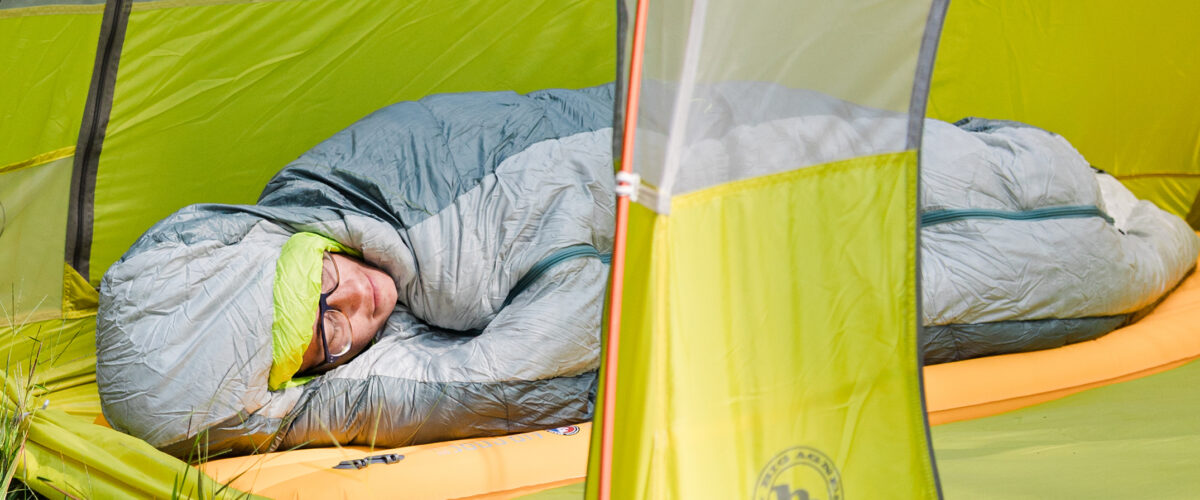 person lying in sleeping bag at campsite