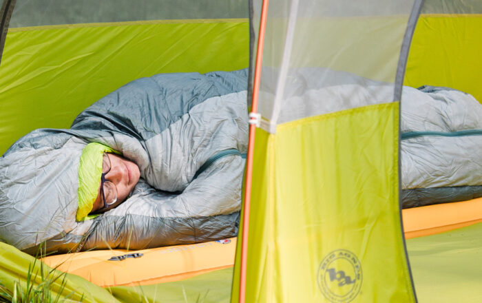person lying in sleeping bag at campsite