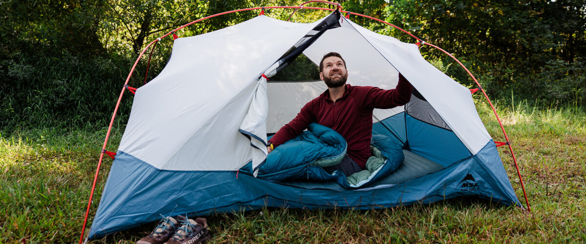 man outdoors in backpacking tent