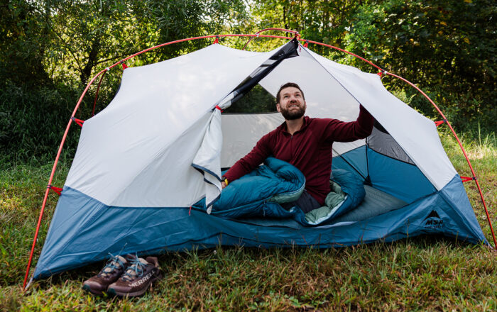 man outdoors in backpacking tent