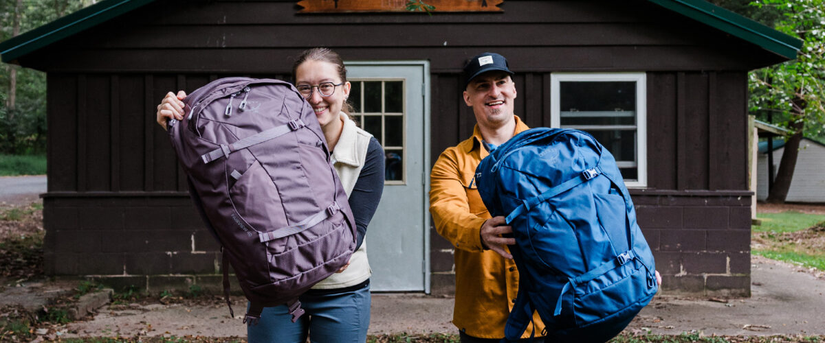 two people outdoors wit Osprey travel packs