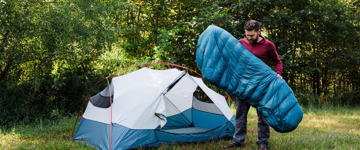 man camping with tent and sleeping bag